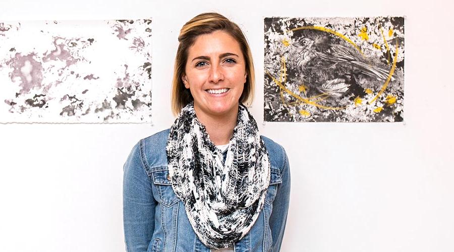  young female student standing in front of 2 paintings